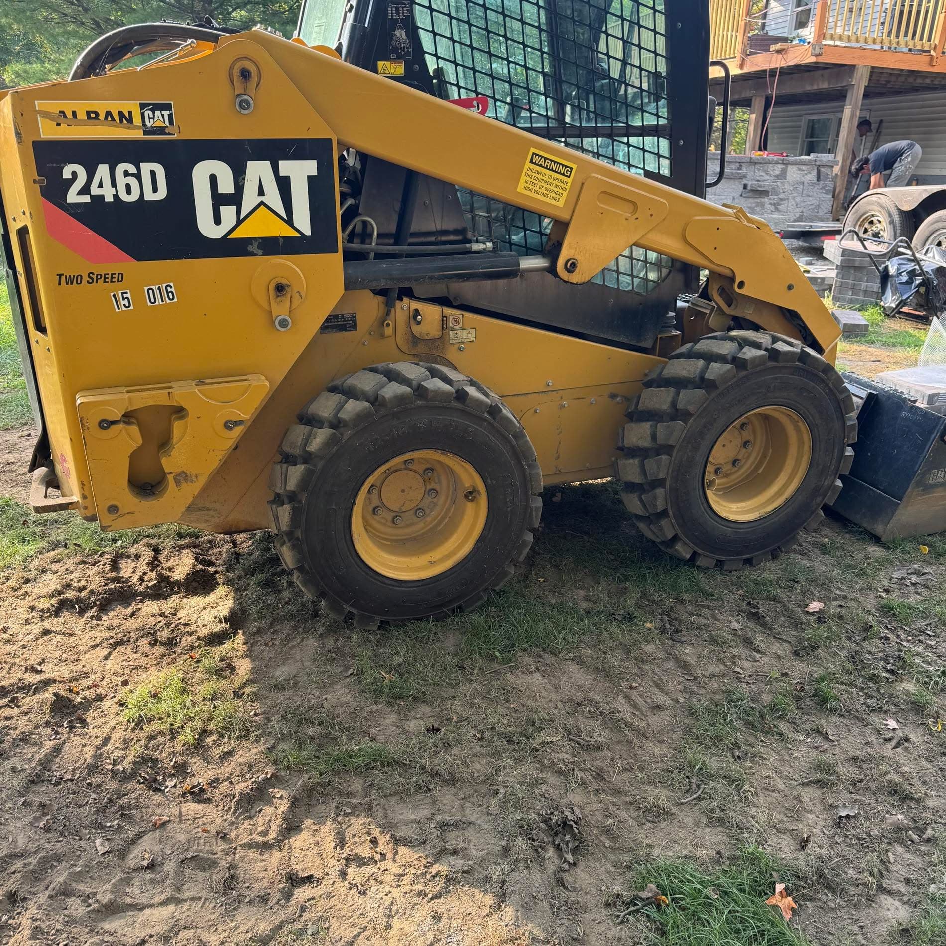 Yellow Caterpillar 246D skid steer loader with large tires on a dirt construction site.